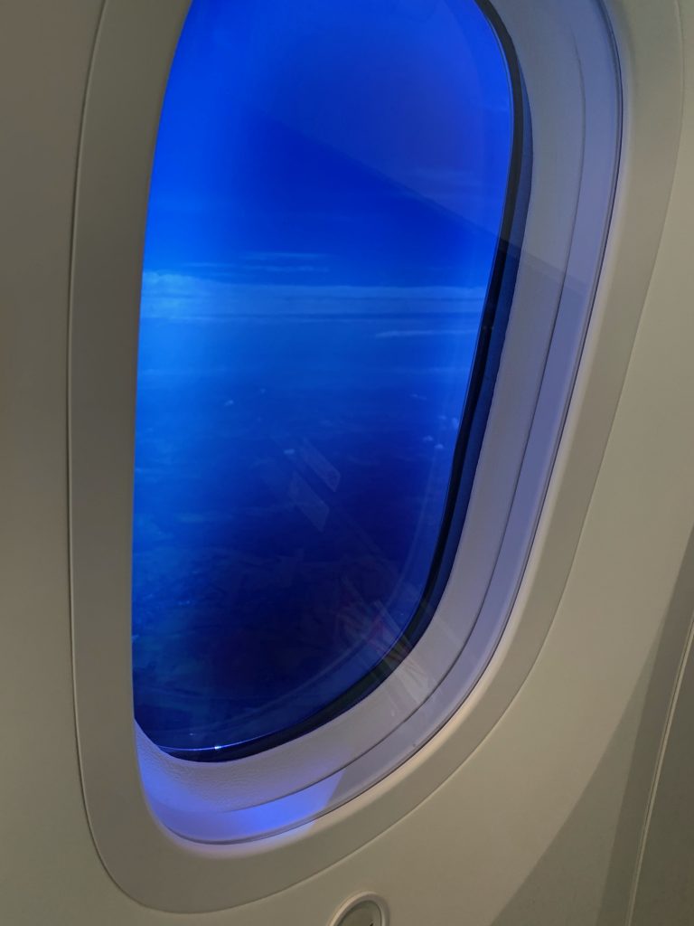 oval-shaped airplane window with view of blue sky