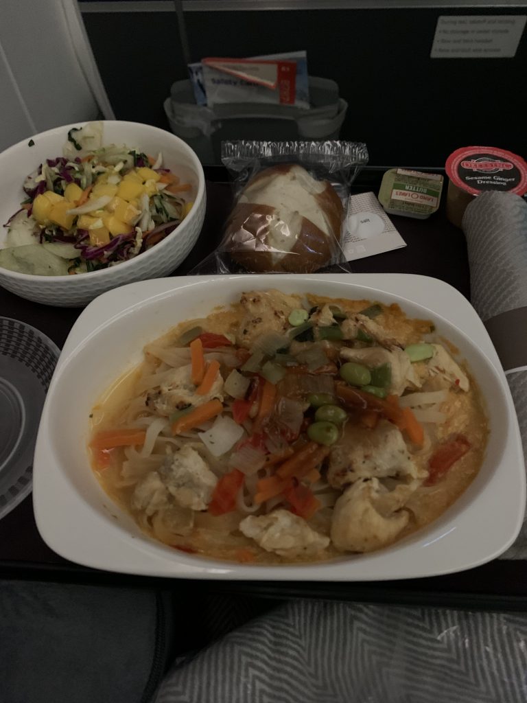 meal on airplance, chicken dish, pretzel rolls, salad